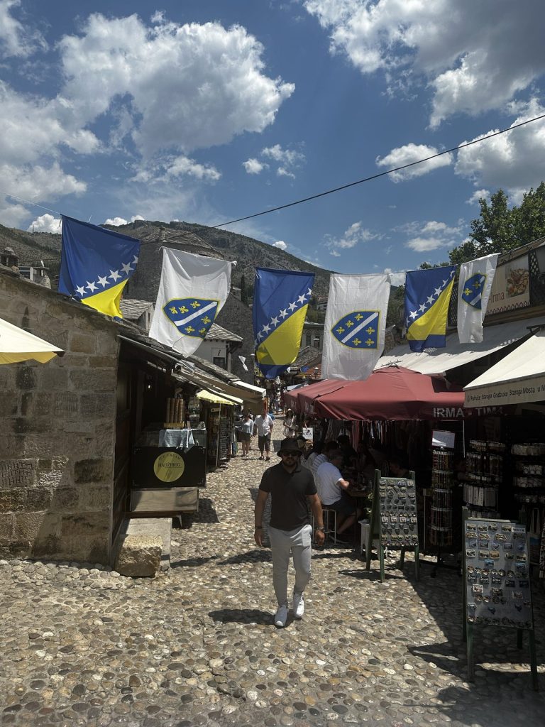 Weiße Lilien-Fahnen und bosnische Staatsflaggen über einer Altstadtgasse in Mostar