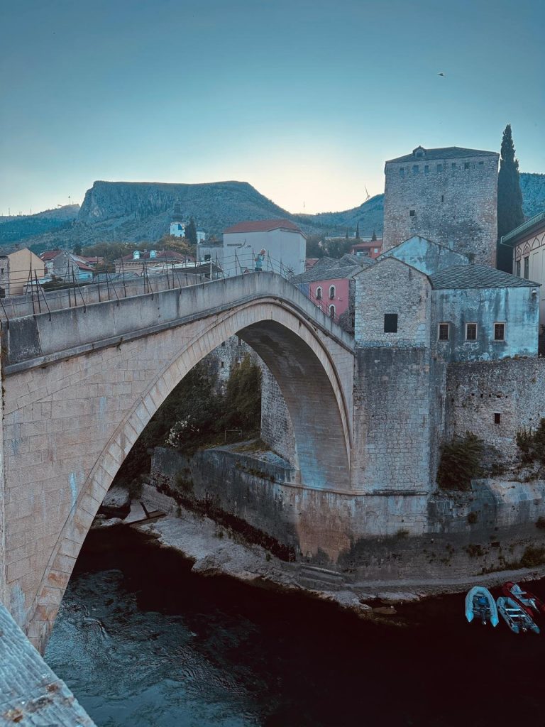 Die wiederaufgebaute Stari Most in Mostar im Morgenlicht, dahinter Altstadt und Berge