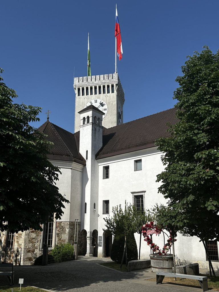 Der Innenhof der Ljubljanska Burg mit dem weißen Turm und der slowenischen Flagge.