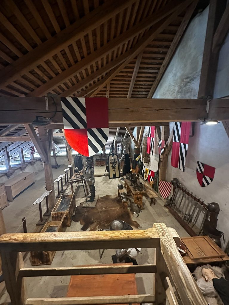 Waffenhalle im Inneren der Burg Predjama mit Bannern und historischem Gerät