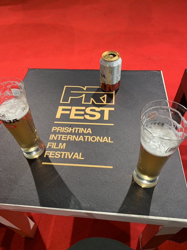 Tisch mit PriFest-Logo und Bier beim Filmfestival in Priština