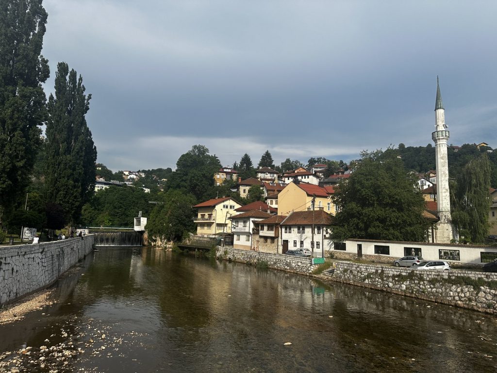 Die Miljacka mit gespiegeltem Minarett und den Häusern der Altstadt von Sarajevo.