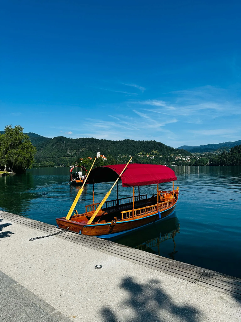 Traditionelle hölzerne Pletna-Boote am Ufer des Bleder Sees, im Hintergrund die Insel