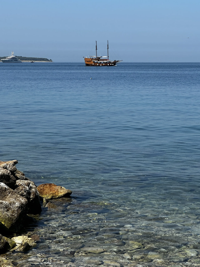 Blick aufs offene Meer mit einem Segelschiff vor der Küste von Piran