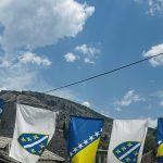 Bosnische Staatsflagge und weiße Lilien-Fahne über einer Gasse in Mostars Altstadt