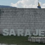 Der Schriftzug „I ♥ Sarajevo" an der Mauer der Weißen Festung, dahinter die bosnische Fahne und die Berge über der Stadt.