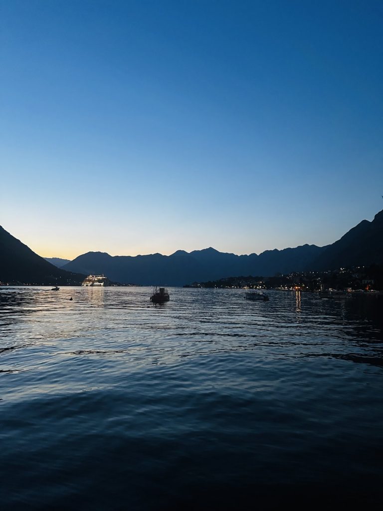 Bucht von Kotor zur blauen Stunde mit Booten auf ruhigem Wasser.