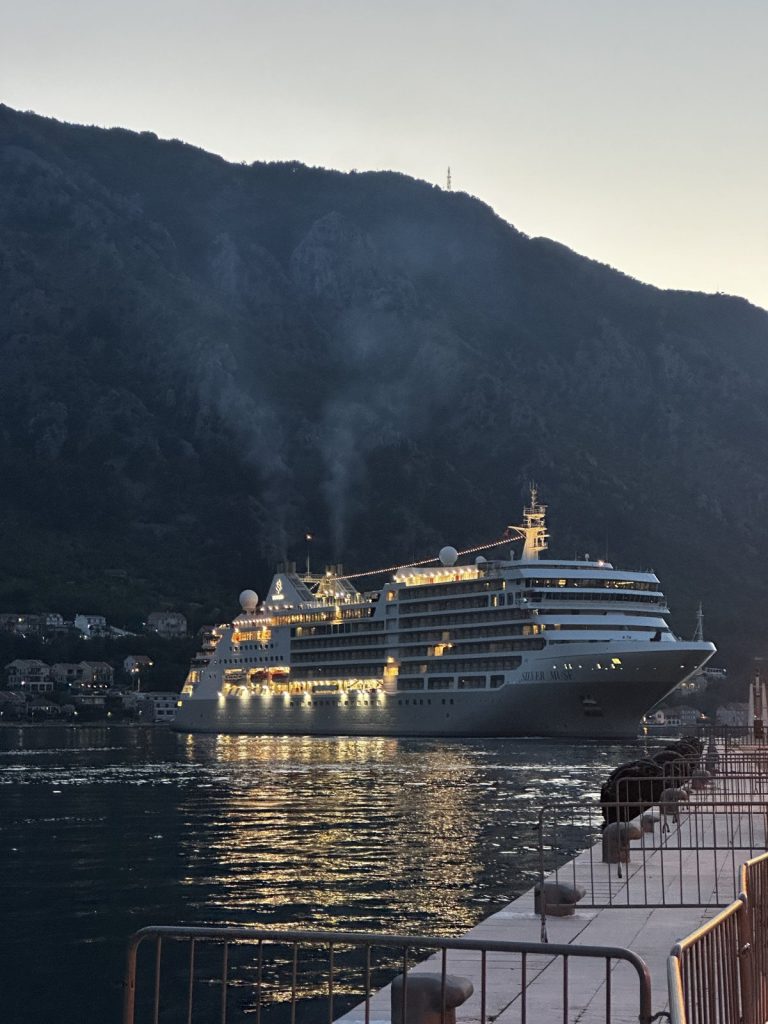 Ein beleuchtetes Kreuzfahrtschiff verlässt bei Nacht die Bucht von Kotor.