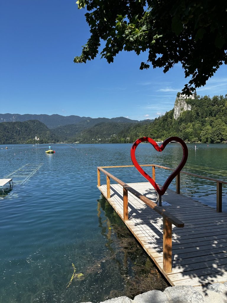 Rotes Herz an einem Bootssteg mit Blick über den Bleder See zur Burg.