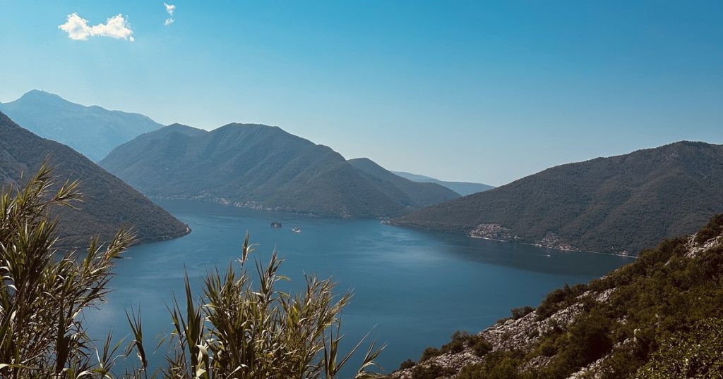 Blick von oben auf die tiefblaue Bucht von Kotor mit steil aufragenden Bergen.