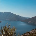 Blick von oben auf die tiefblaue Bucht von Kotor mit steil aufragenden Bergen.